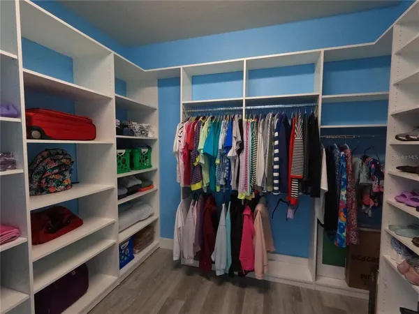 a view of walk in closet with clothes and shoes
