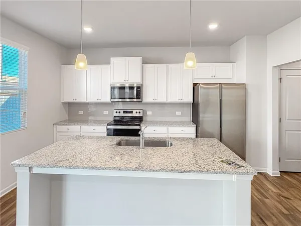 a kitchen with kitchen island granite countertop a refrigerator a sink a stove a microwave and island