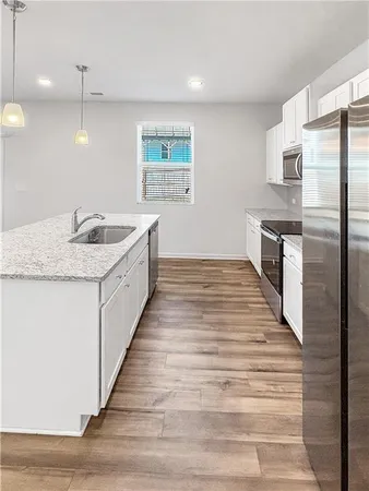 a large kitchen with a stove a sink dishwasher a refrigerator and wooden floor