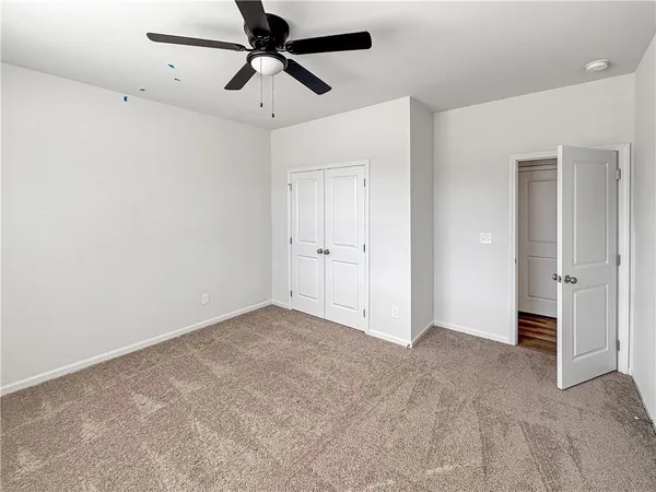 an empty room with closet and a ceiling fan