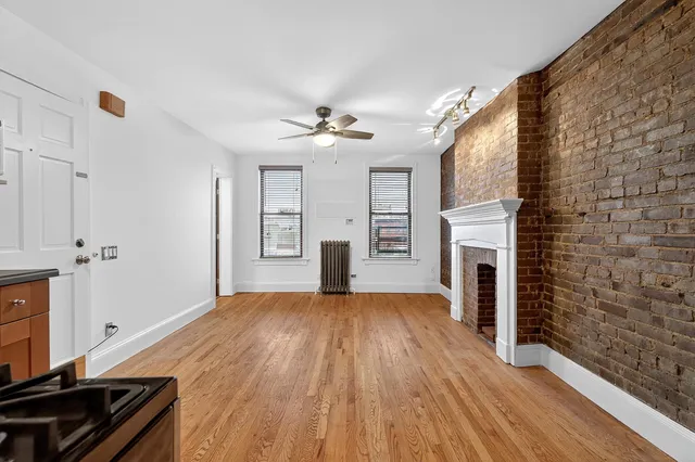 a view of a livingroom with a fireplace a ceiling fan and windows