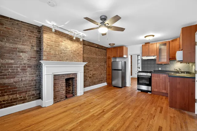 a open kitchen with stainless steel appliances granite countertop a stove top oven a refrigerator and a fireplace