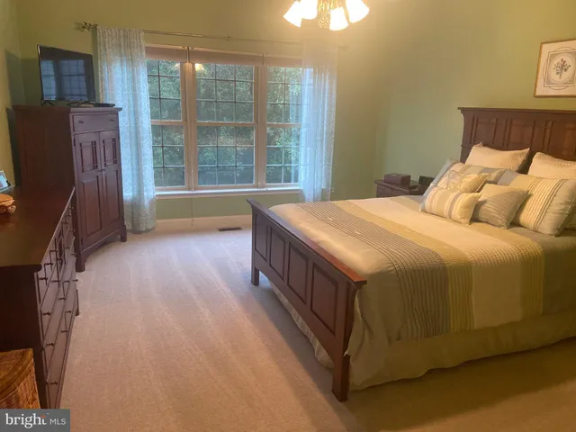 a spacious bedroom with a bed and wooden floor