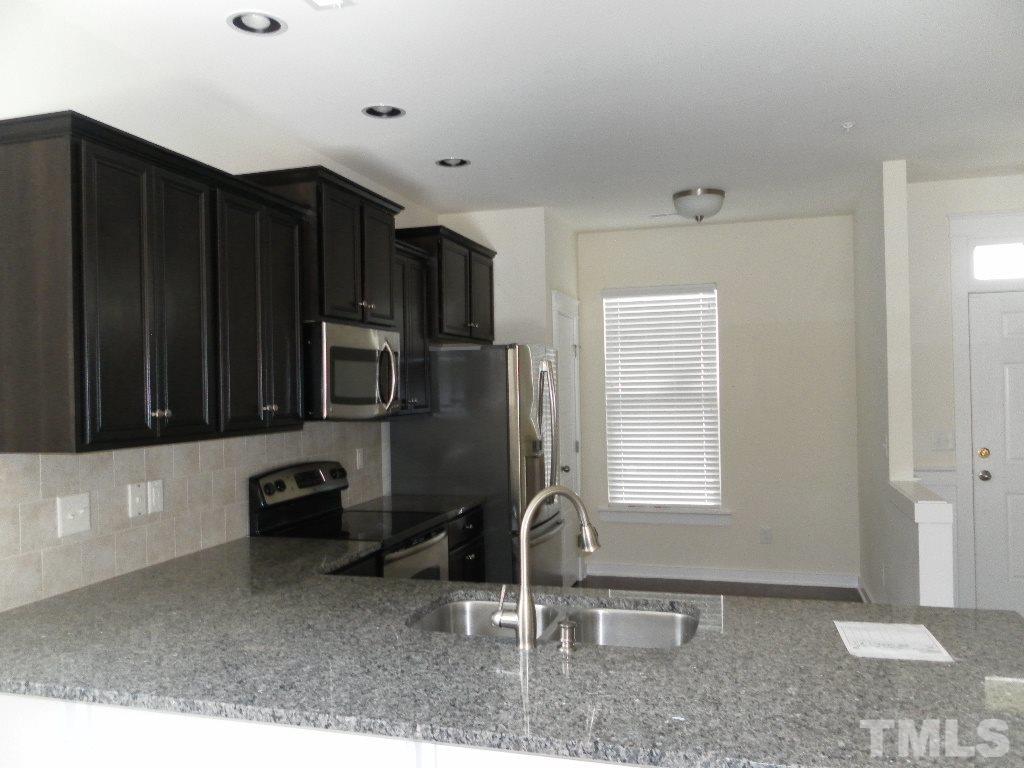 7828 Allscott Way Raleigh, NC 27612 - Photo 8 of 17 a kitchen with wooden cabinets and a sink