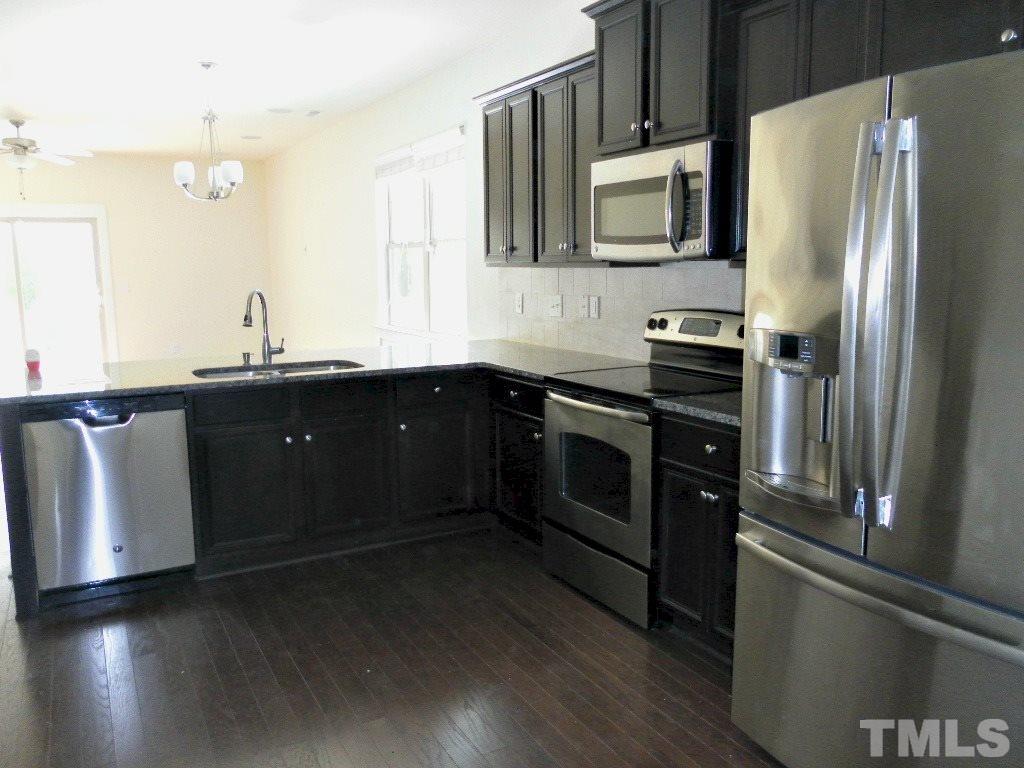 7828 Allscott Way Raleigh, NC 27612 - Photo 9 of 17 a kitchen with stainless steel appliances and wooden cabinets