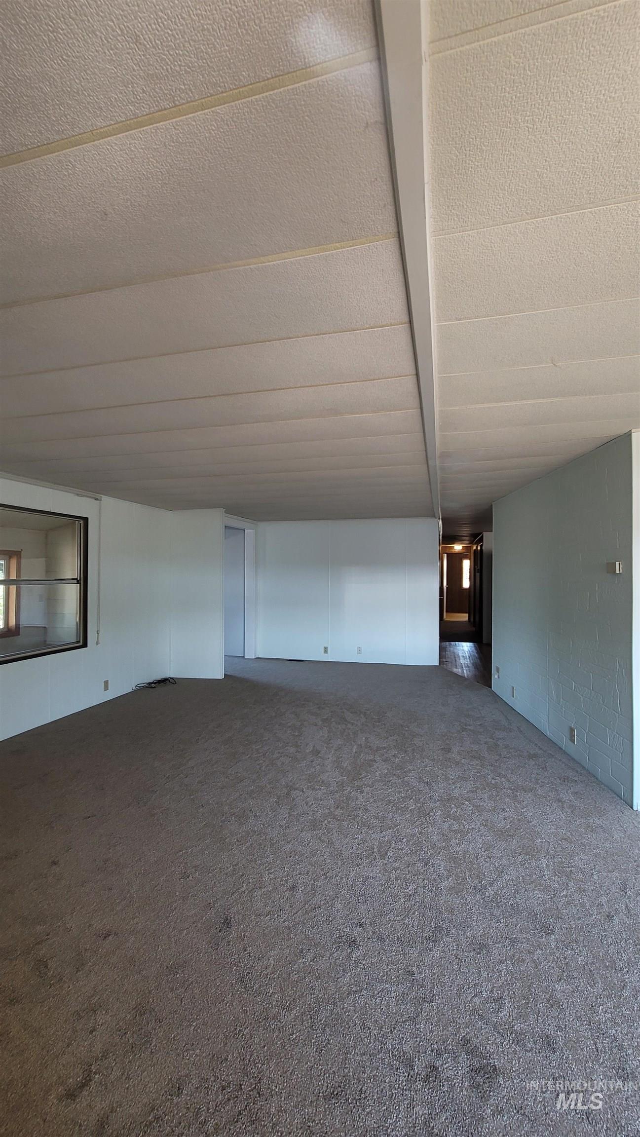 2122 Highway 95 Council, ID 83612 - Photo 8 of 31 Unfurnished living room featuring a textured ceiling and dark colored carpet