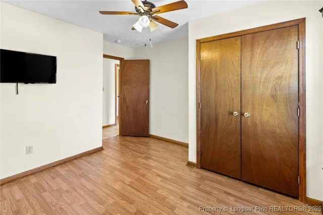 an empty room with wooden floor chandelier fan and windows
