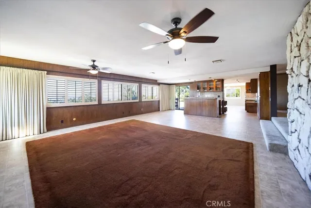 a living room with a fireplace furniture a ceiling fan and a rug