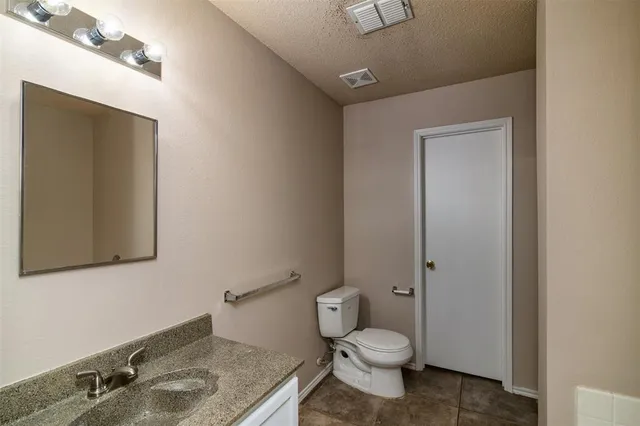 a bathroom with a granite countertop toilet and sink