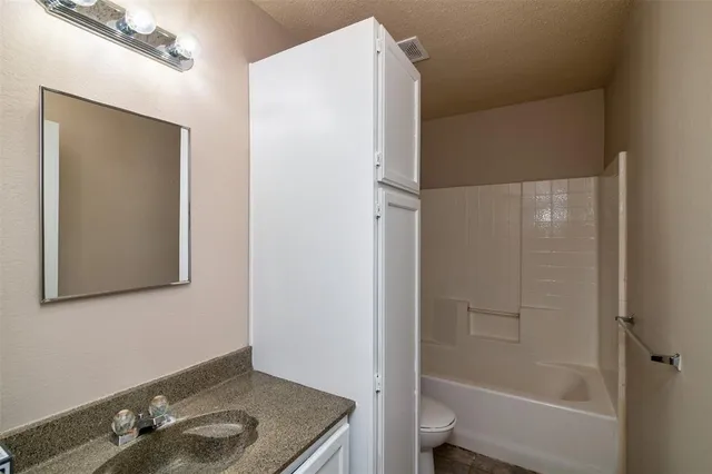 a bathroom with a granite countertop sink mirror and toilet