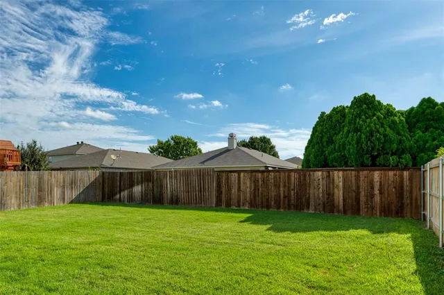 a view of a backyard with table and chairs and wooden fence