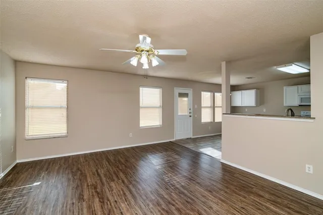 a view of an empty room with a window and wooden floor