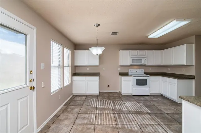 a large white kitchen with a white cabinets and chandelier