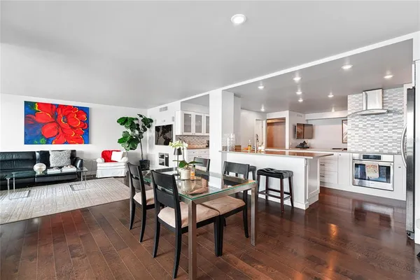 a kitchen with stainless steel appliances kitchen island granite countertop a dining table chairs and view living room