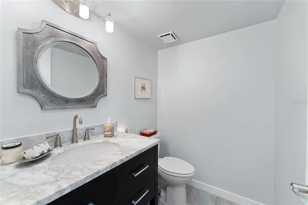 a bathroom with a granite countertop sink mirror vanity and toilet