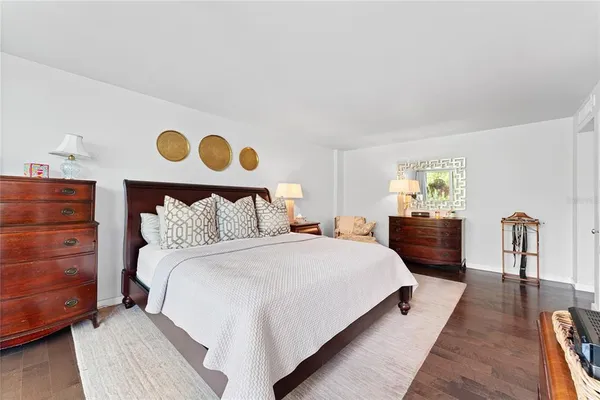 a large bedroom with a bed and dresser with wooden floor