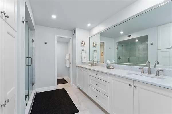 a spacious bathroom with a double vanity sink a mirror and a shower