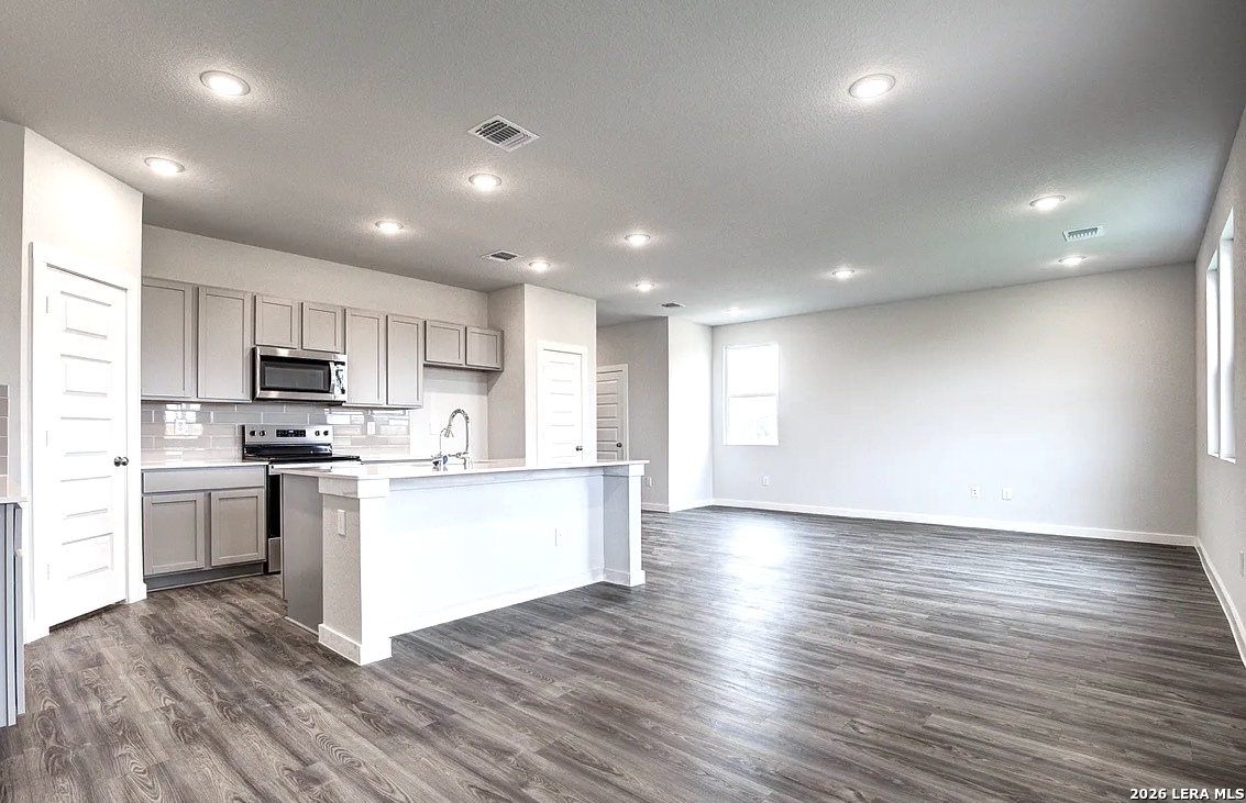 2563 Rambo Drive San Antonio, TX 78224 - Photo 6 of 21 a kitchen with stainless steel appliances granite countertop a stove top oven a sink dishwasher a refrigerator and white cabinets with wooden floor