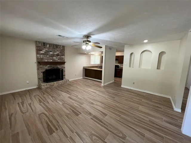 an empty room with wooden floor fireplace and windows