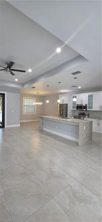 598 2nd Street Southeast Naples, FL 34117 - Photo 40 of 40 Kitchen featuring white cabinetry, hanging light fixtures, a spacious island, light stone countertops, and open floor plan