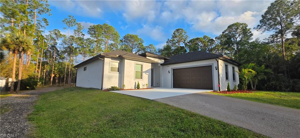 598 2nd Street Southeast Naples, FL 34117 - Photo 3 of 40 View of front of property with stucco siding, an attached garage, driveway, and a front lawn
