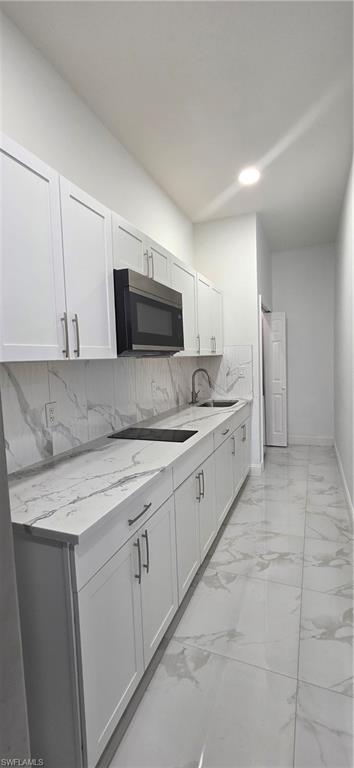 598 2nd Street Southeast Naples, FL 34117 - Photo 36 of 40 Kitchen featuring light marble finish floors, light stone counters, white cabinetry, tasteful backsplash, and cooktop