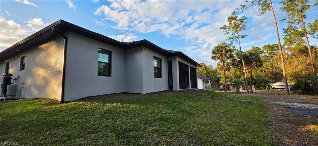 598 2nd Street Southeast Naples, FL 34117 - Photo 8 of 40 View of side of property featuring stucco siding, a lawn, and a sunroom