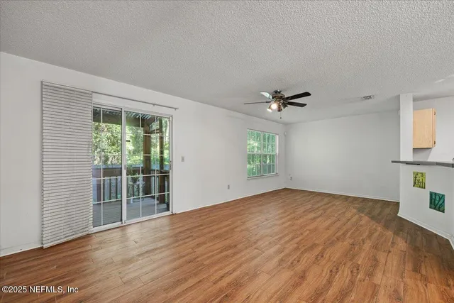 a view of an empty room with a window and wooden floor