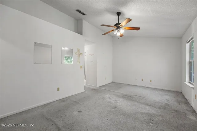 an empty room with windows and fan