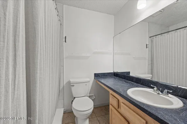 a bathroom with a granite countertop sink toilet and a mirror