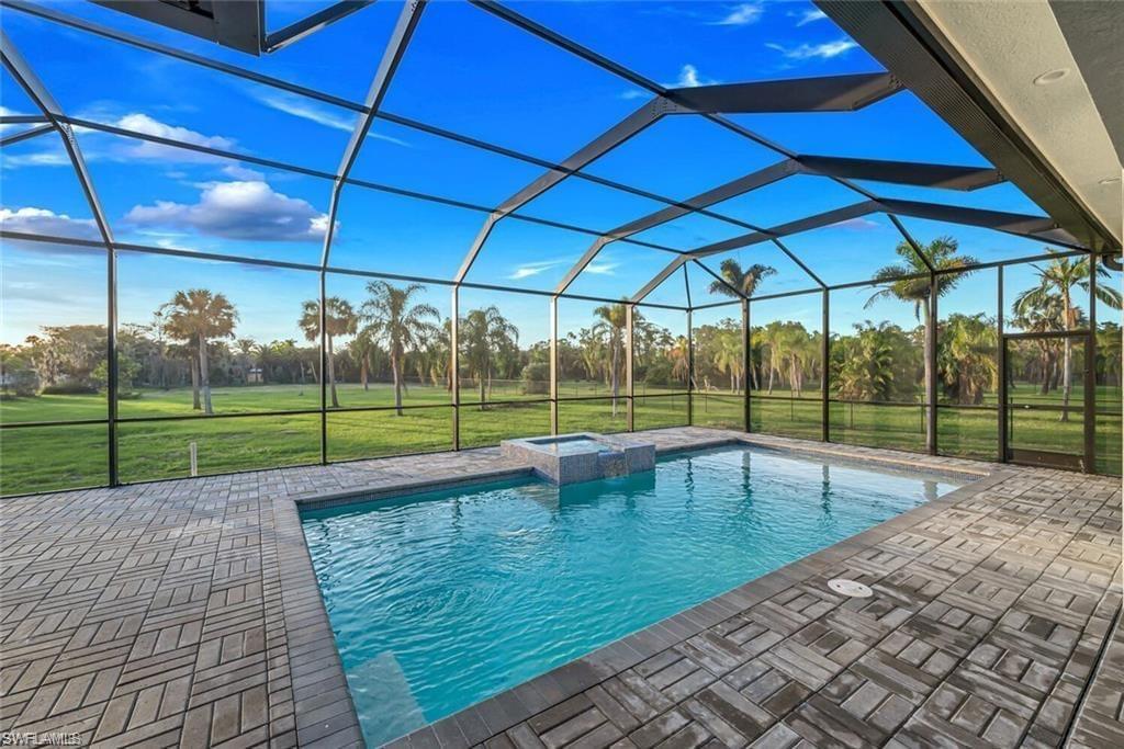 687 23rd Street Southwest Naples, FL 34117 - Photo 20 of 40 View of swimming pool featuring a sunroom, a lawn, a lanai, and a pool with connected hot tub