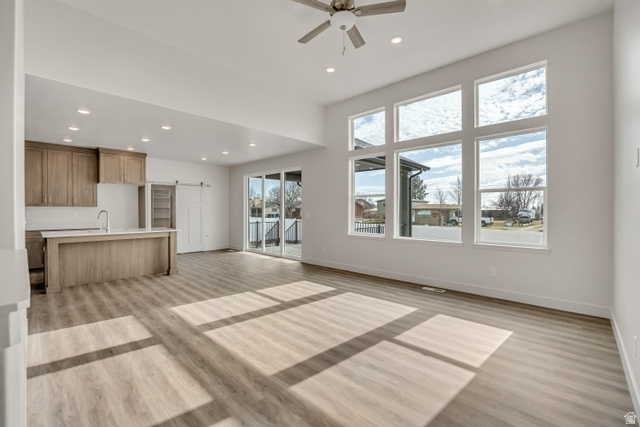 3839 West 825 North, Unit WF18 West Point, UT 84015 - Photo 4 of 22 Unfurnished living room featuring recessed lighting, a barn door, ceiling fan, light wood-type flooring, and a high ceiling
