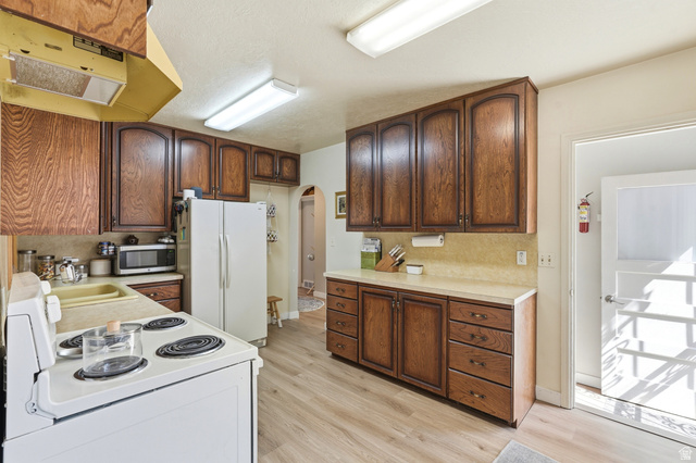 270 East 700 North Logan, UT 84321 - Photo 8 of 42 Kitchen featuring wood-finish cabinetry, light-toned countertops, and wood-finish flooring