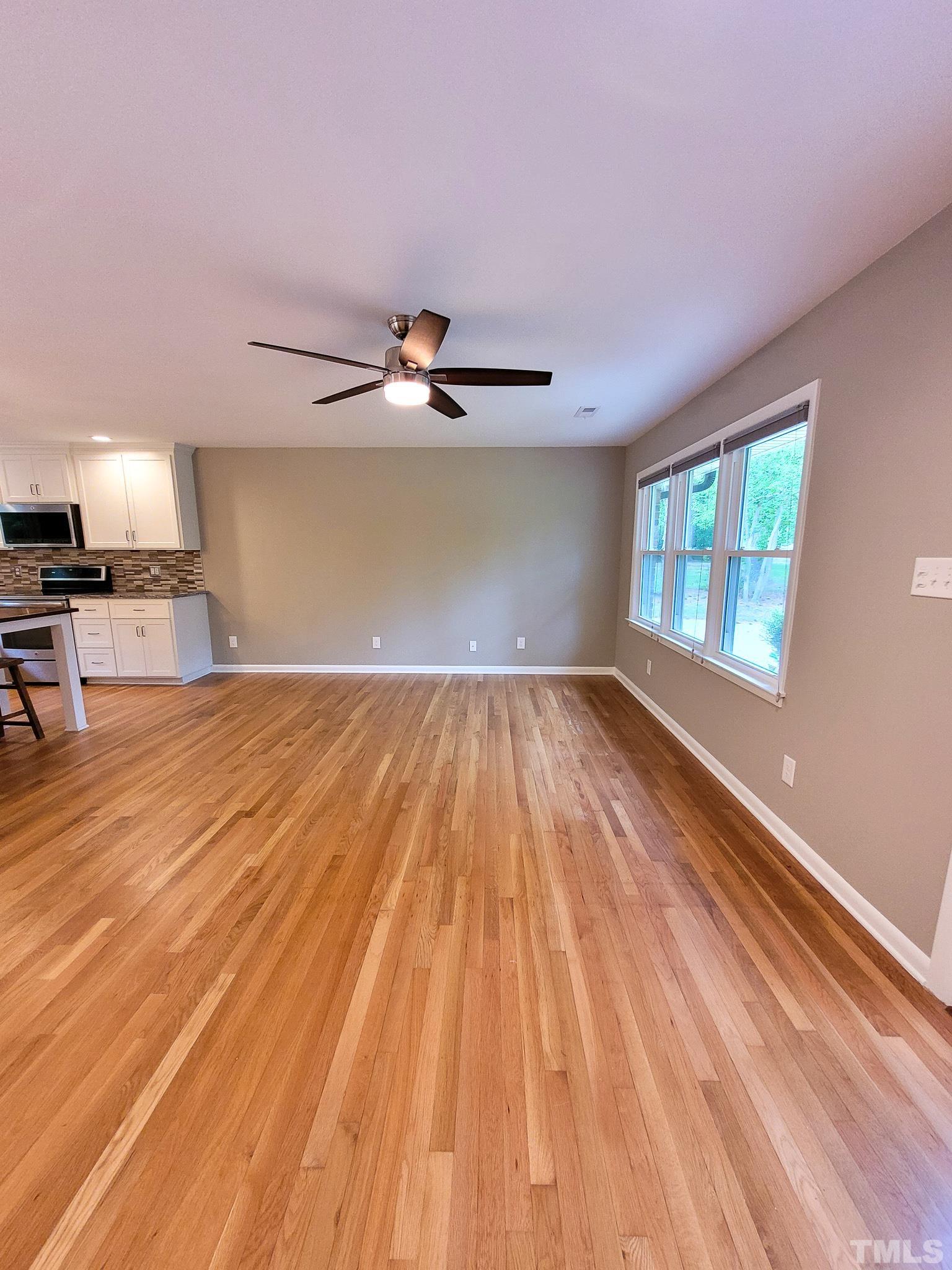 6708 Johnsdale Road Raleigh, NC 27615 - Photo 7 of 44 a view of a livingroom with wooden floor and a ceiling fan