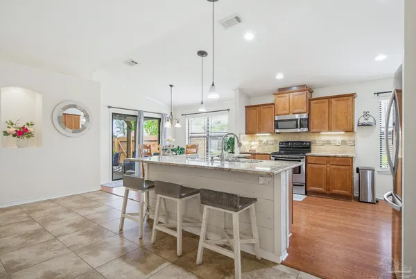a kitchen with stainless steel appliances granite countertop wooden floor dining table and chairs