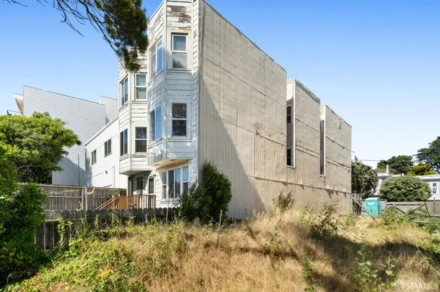 a view of a large white building with a yard