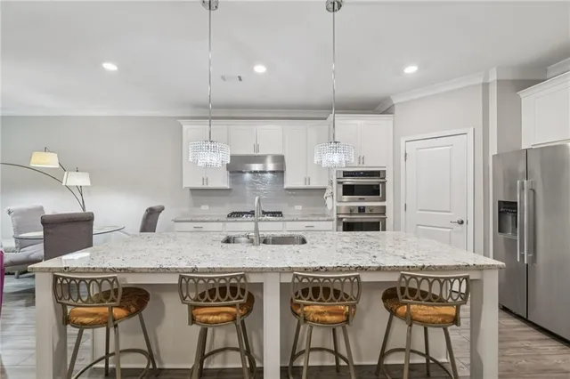a kitchen with stainless steel appliances kitchen island granite countertop a stove a sink and a refrigerator