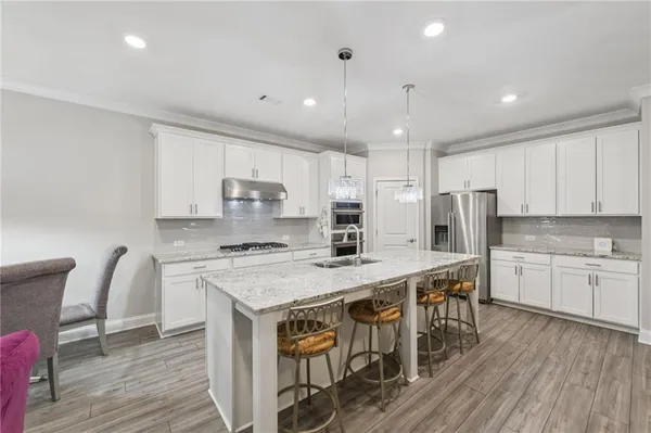 a kitchen with stainless steel appliances kitchen island granite countertop a stove a refrigerator and a wooden cabinets