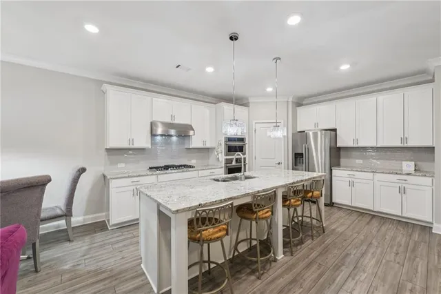 a kitchen with stainless steel appliances kitchen island granite countertop a stove a refrigerator and a wooden cabinets