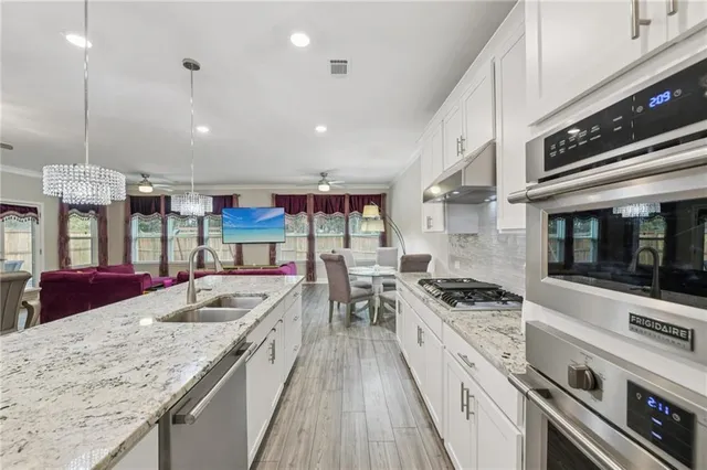 a kitchen with stainless steel appliances kitchen island granite countertop a table chairs and a refrigerator