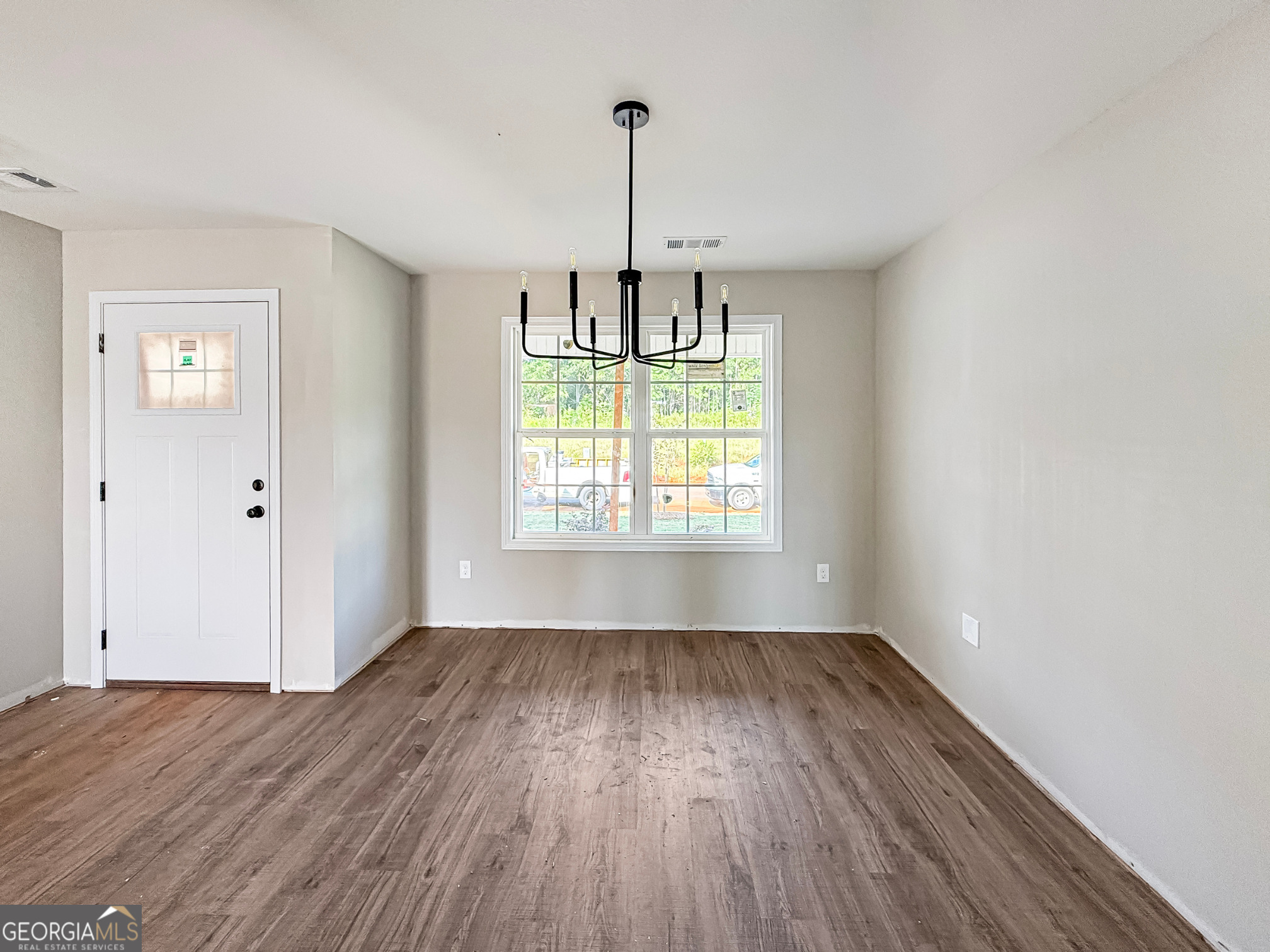 206 Sutton Drive Perry, GA 31069 - Photo 5 of 27 an empty room with wooden floor chandelier and windows
