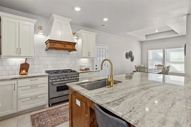 a kitchen with stainless steel appliances granite countertop a stove a sink and a white cabinets