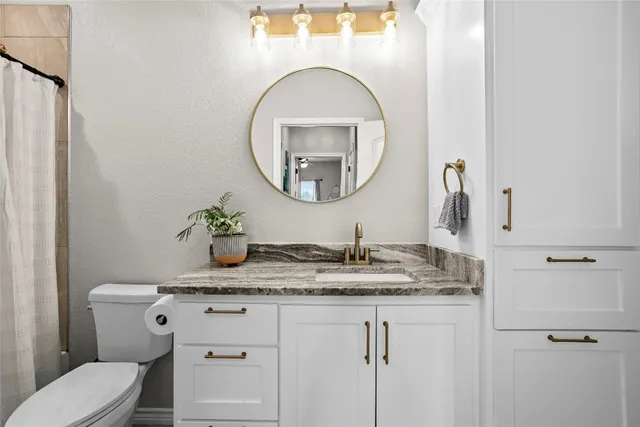 a bathroom with a granite countertop toilet sink and mirror