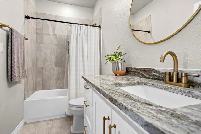 a bathroom with a granite countertop sink a toilet and a bathtub