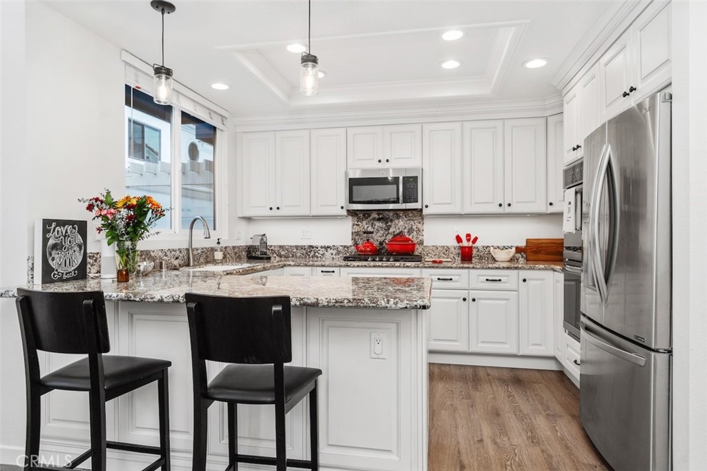 19451 Pompano Lane, Unit 110 Huntington Beach, CA 92648 - Photo 14 of 54 a kitchen with kitchen island granite countertop a sink cabinets and stainless steel appliances