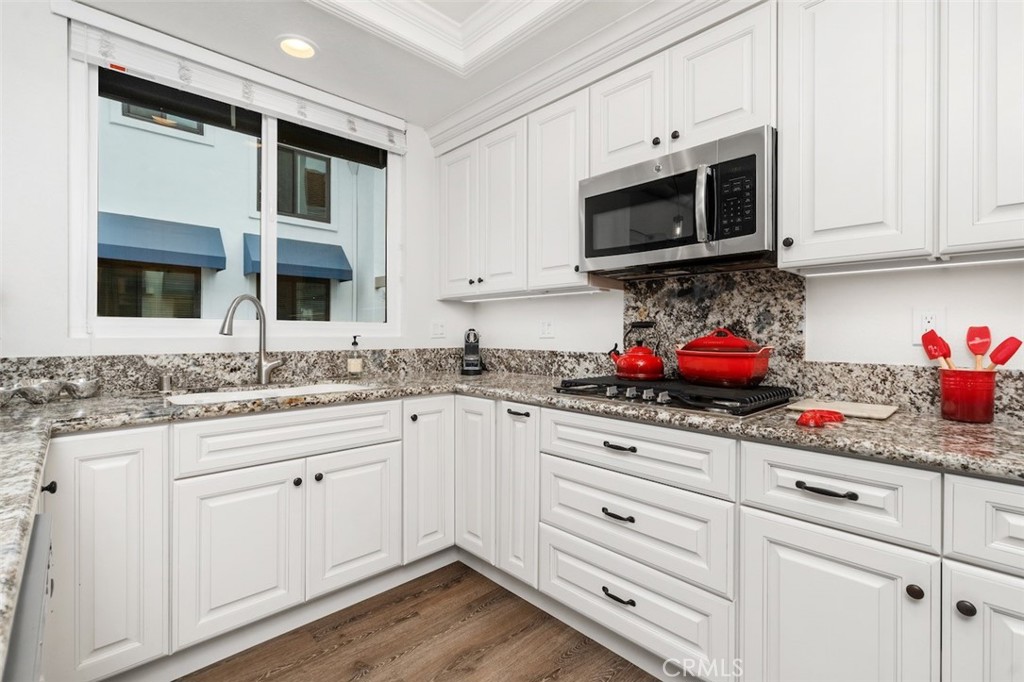 19451 Pompano Lane, Unit 110 Huntington Beach, CA 92648 - Photo 16 of 54 a kitchen with granite countertop white cabinets stainless steel appliances and sink