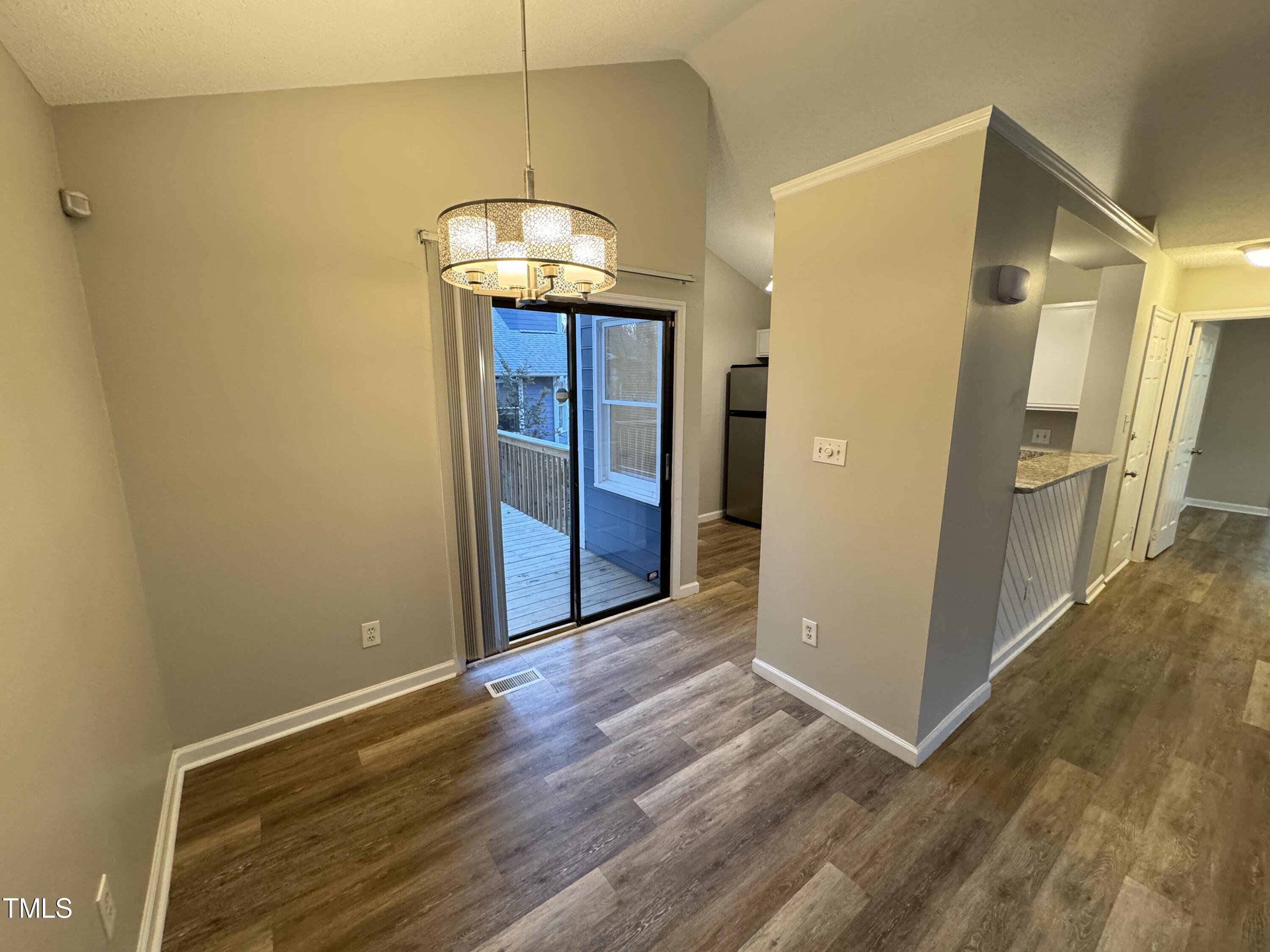456 Dickens Drive Raleigh, NC 27610 - Photo 12 of 33 an empty room with wooden floor and chandelier
