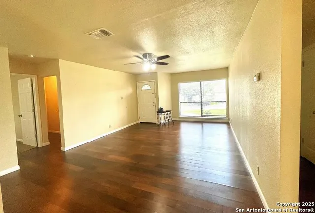 a view of empty room with wooden floor and fan