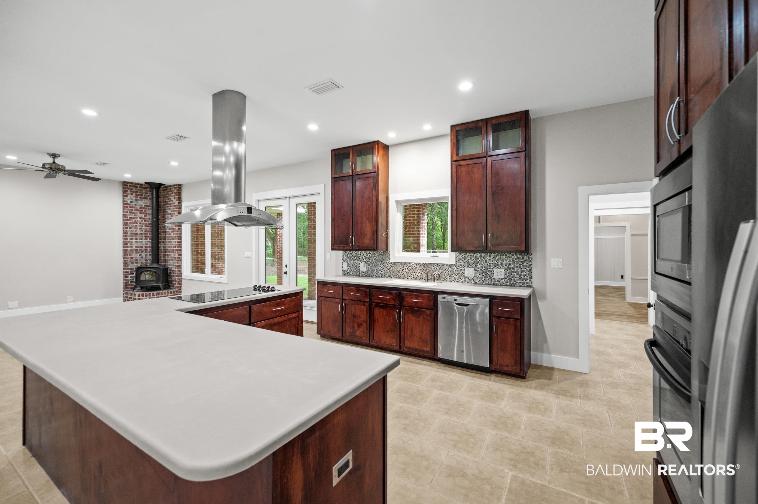 15031 Timber Ridge Drive Loxley, AL 36551 - Photo 14 of 43 Kitchen with black appliances, island range hood, a wood stove, backsplash, and ceiling fan