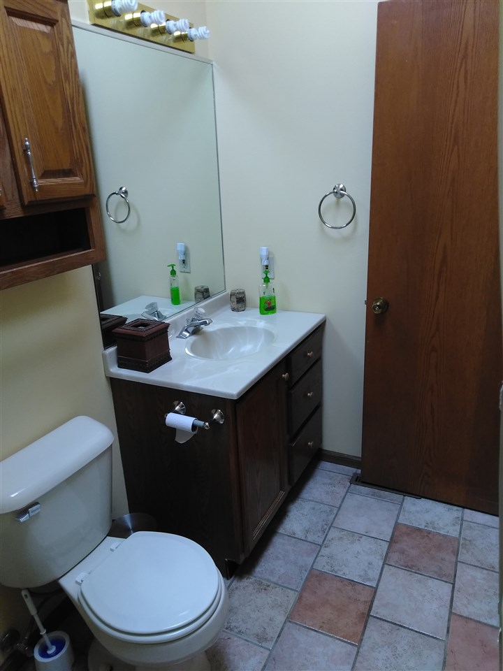 1039 South Trainer Road Rockford, IL 61108 - Photo 8 of 18 a bathroom with a granite countertop sink a toilet a mirror and vanity